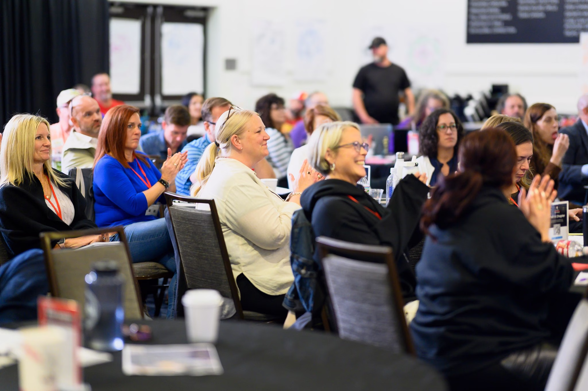 Business leaders at round tables laughing and applauding during a working session